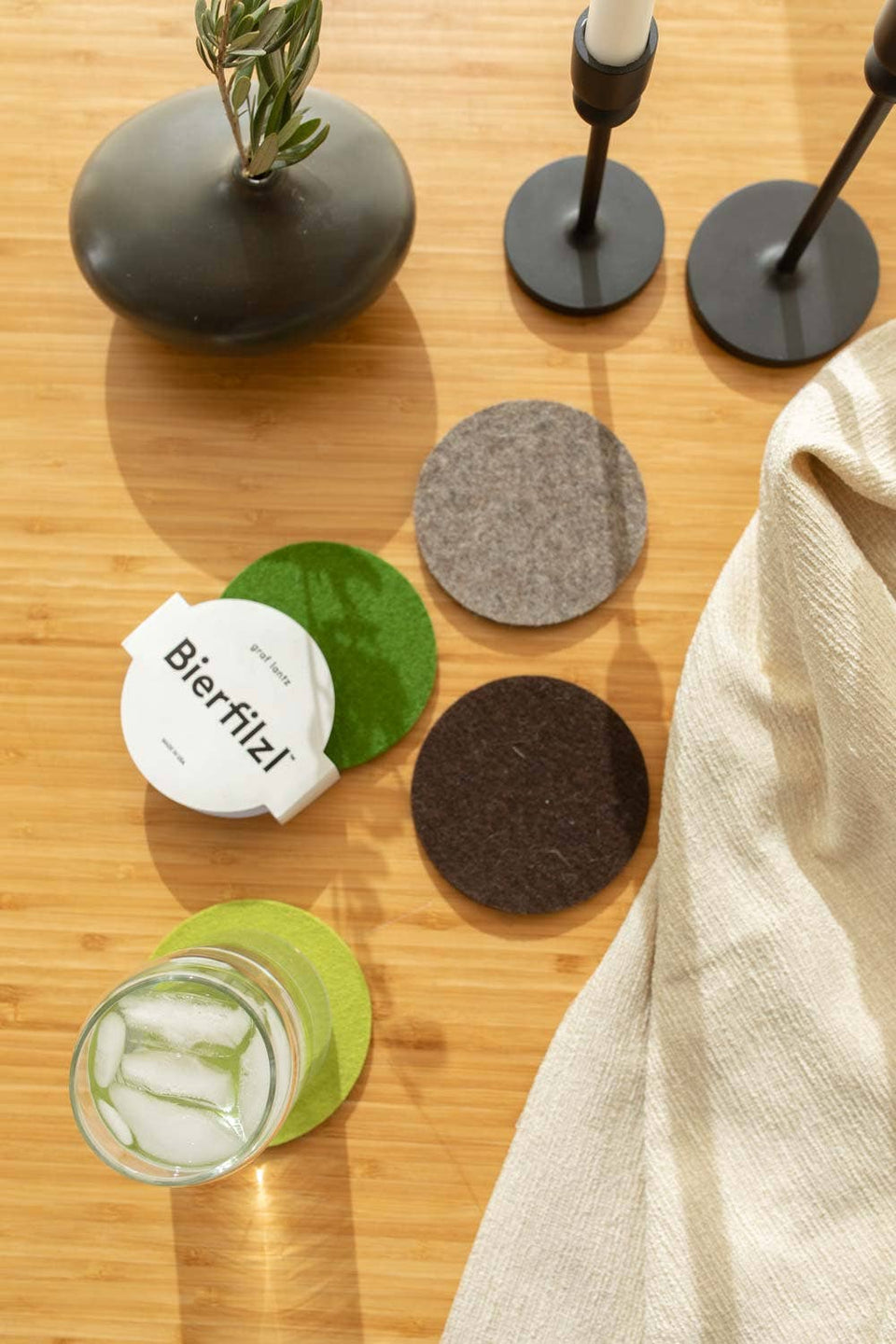 Set of coasters on a wooden surface with a glass of water and a bottle.