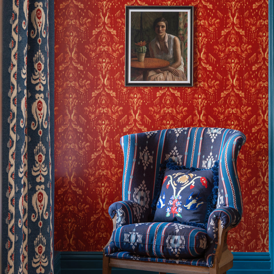 Ancestral Ikat Copper wallpaper by MINDTHEGAP, shown in a furnished interior.