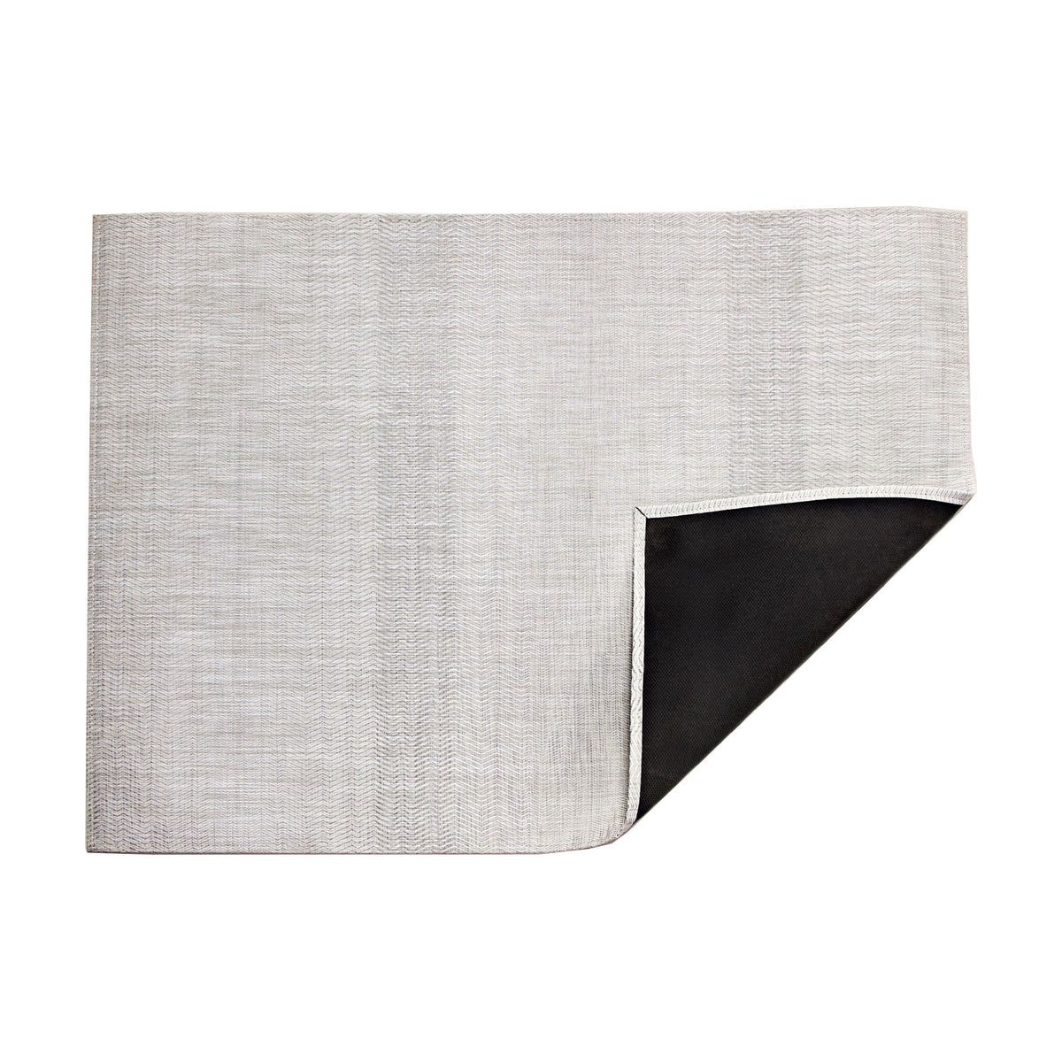 Wave / Grey woven floor mat by Chilewich, folded-corner studio view