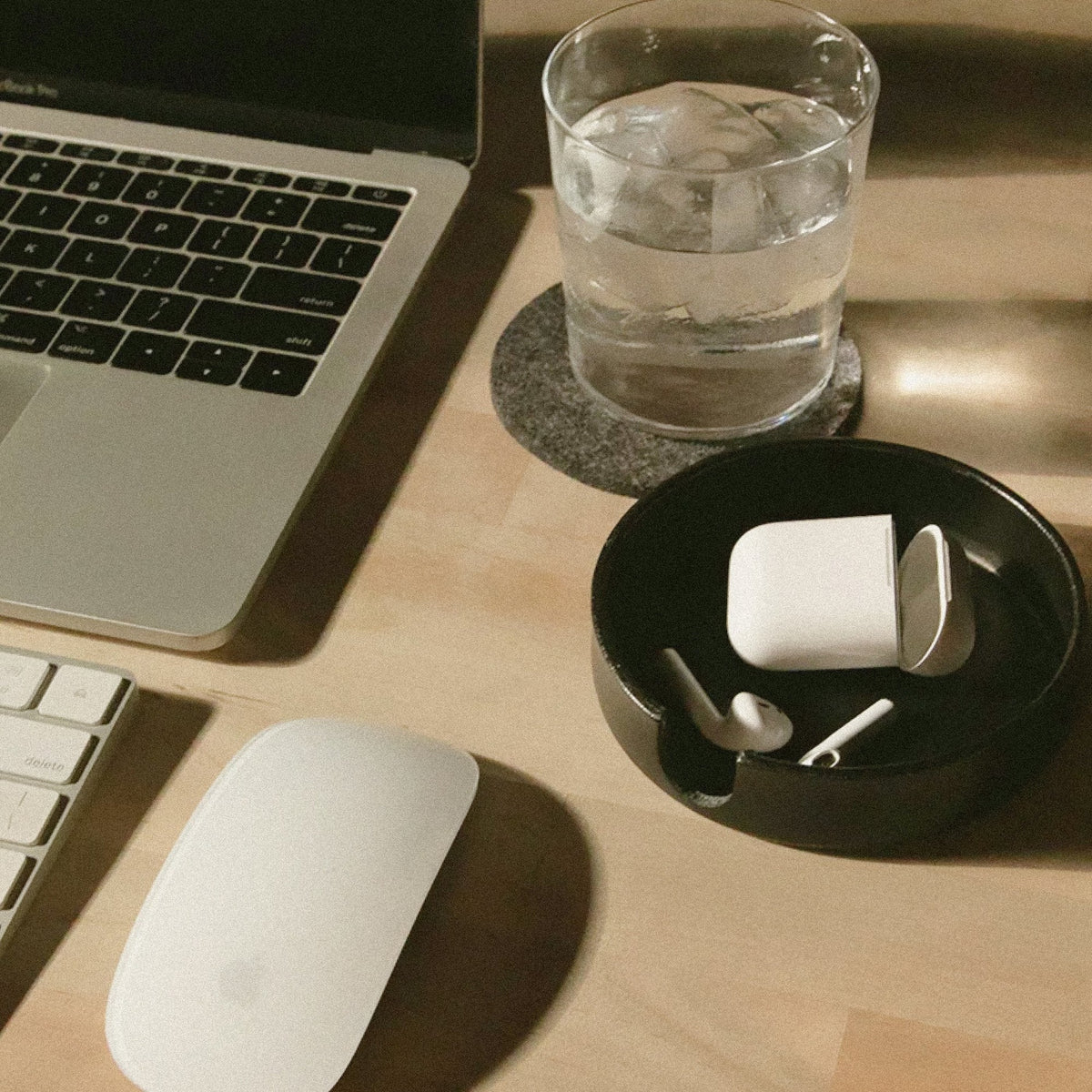 Graf Lantz Black Kobon round tray with earbuds beside a laptop and computer mouse