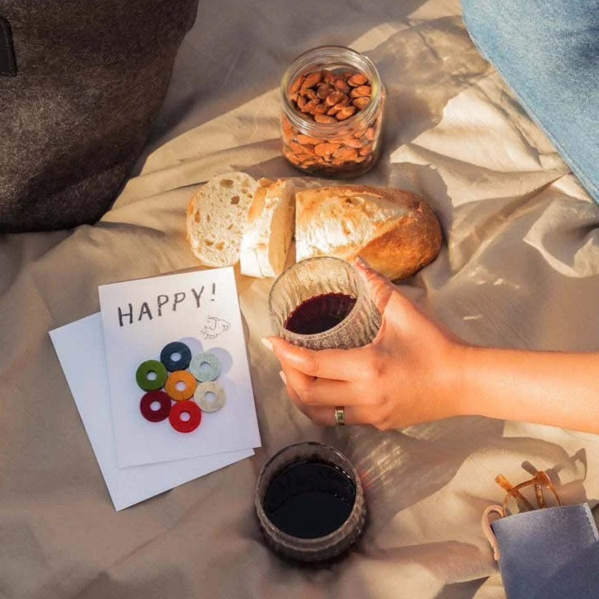 Graf Lantz Happy Wine-Ote’s card beside wine and snacks on a picnic blanket