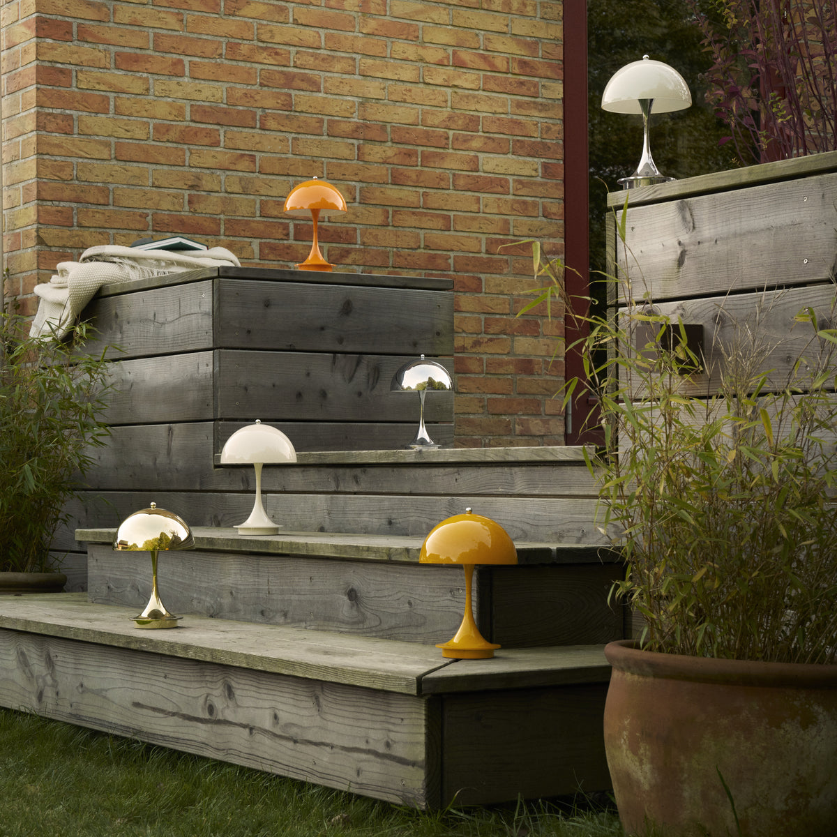 Panthella 160 Portable lamps in several finishes arranged on outdoor timber steps.