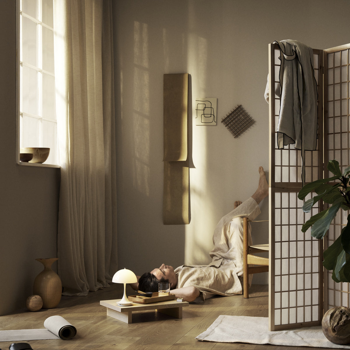 Opal Beige Panthella 160 Portable lamp beside a reader in a softly lit interior.