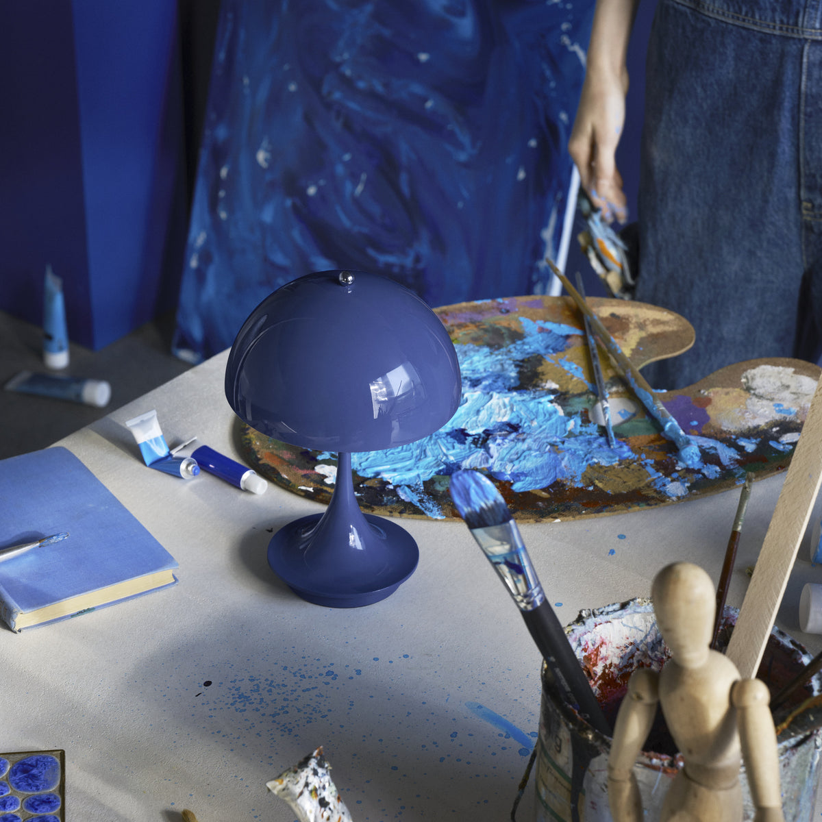 Opaque Indigo Blue Panthella 160 Portable lamp on an artist’s blue work table.