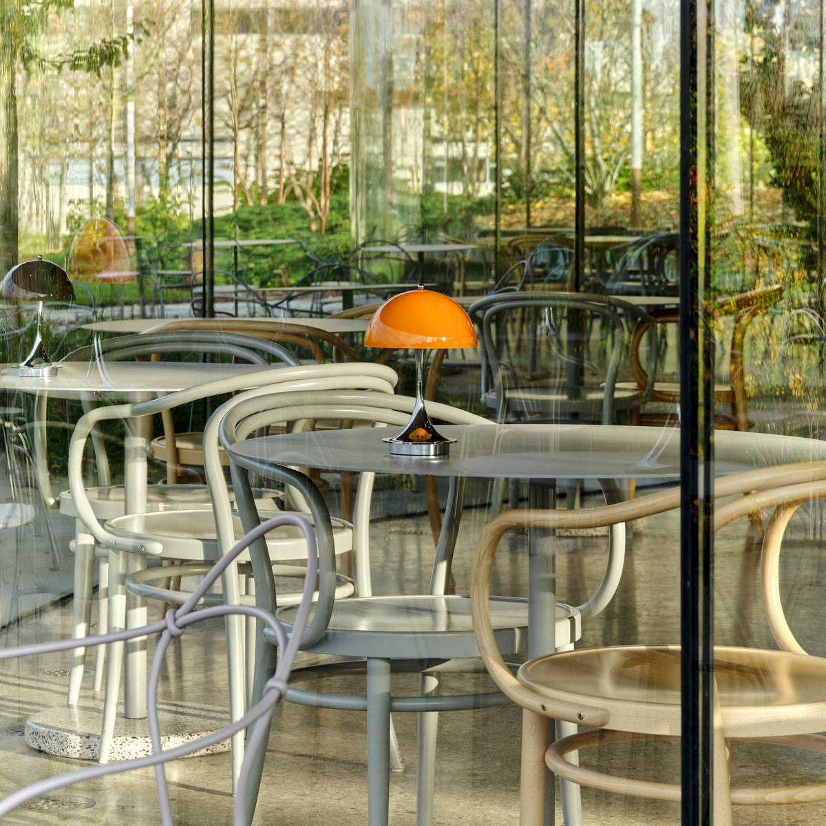 Original Opal Orange Panthella 160 Portable lamp with chrome base on a greenhouse café table.
