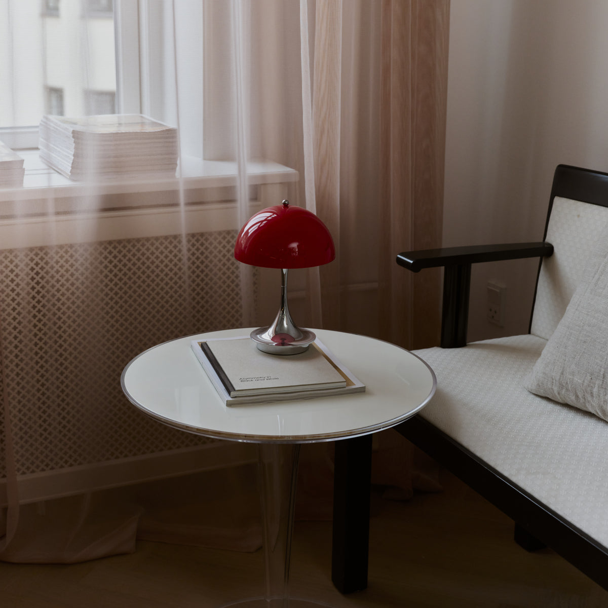 Original Opal Red Panthella 160 Portable lamp on a white table beside a lounge chair.