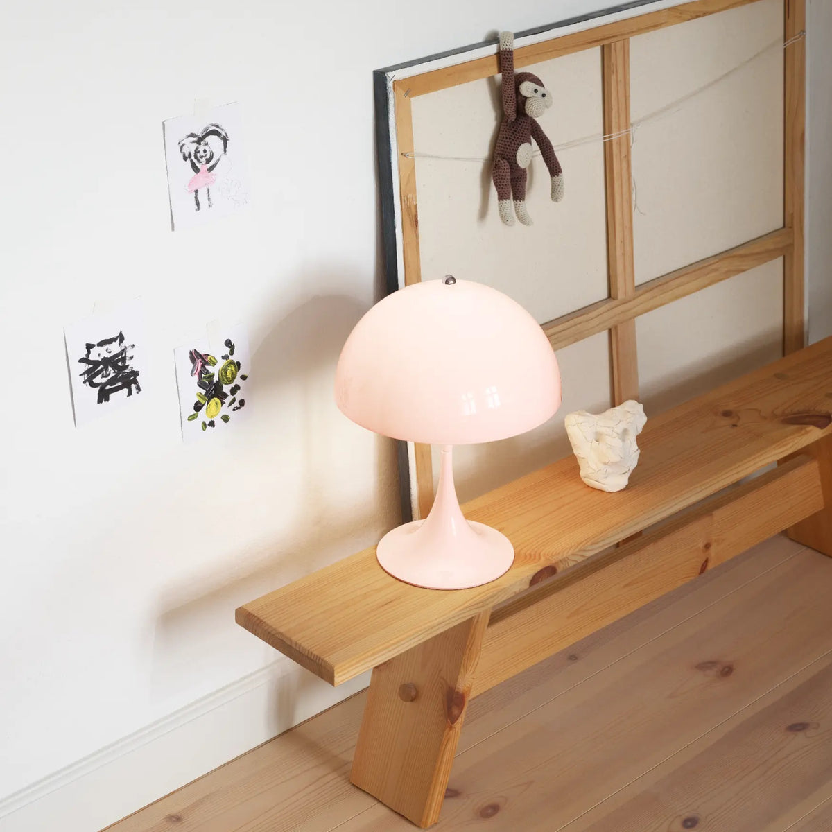 Opal Pale Rose Panthella 250 Portable Lamp glowing on a wooden bench.
