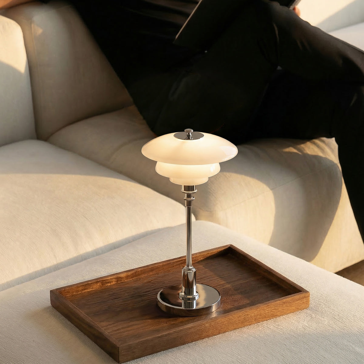 Chrome PH 1/1 Portable Lamp illuminated on a wooden tray beside a sofa.