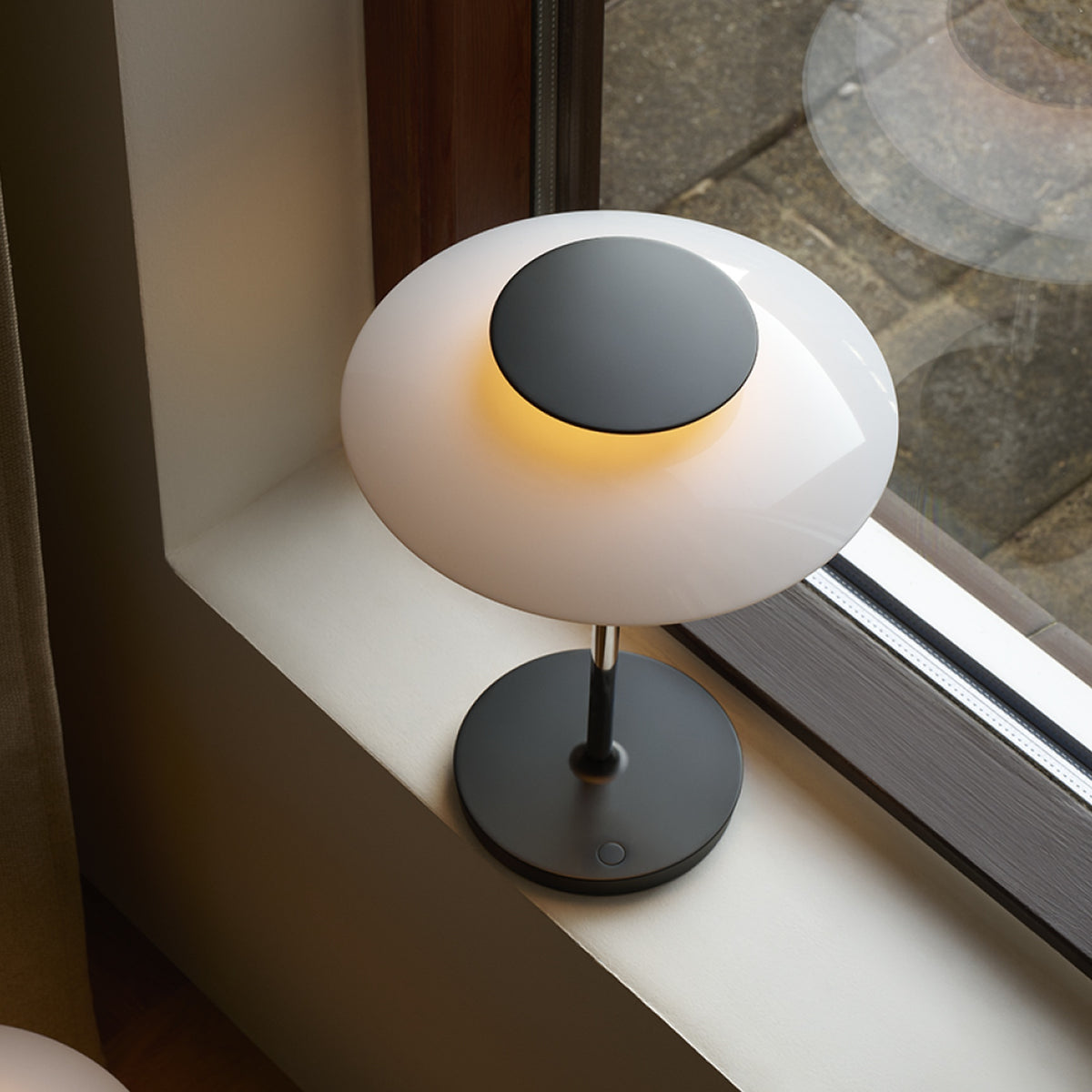 Chrome PH 80 Portable Lamp illuminated on a windowsill, viewed from above.