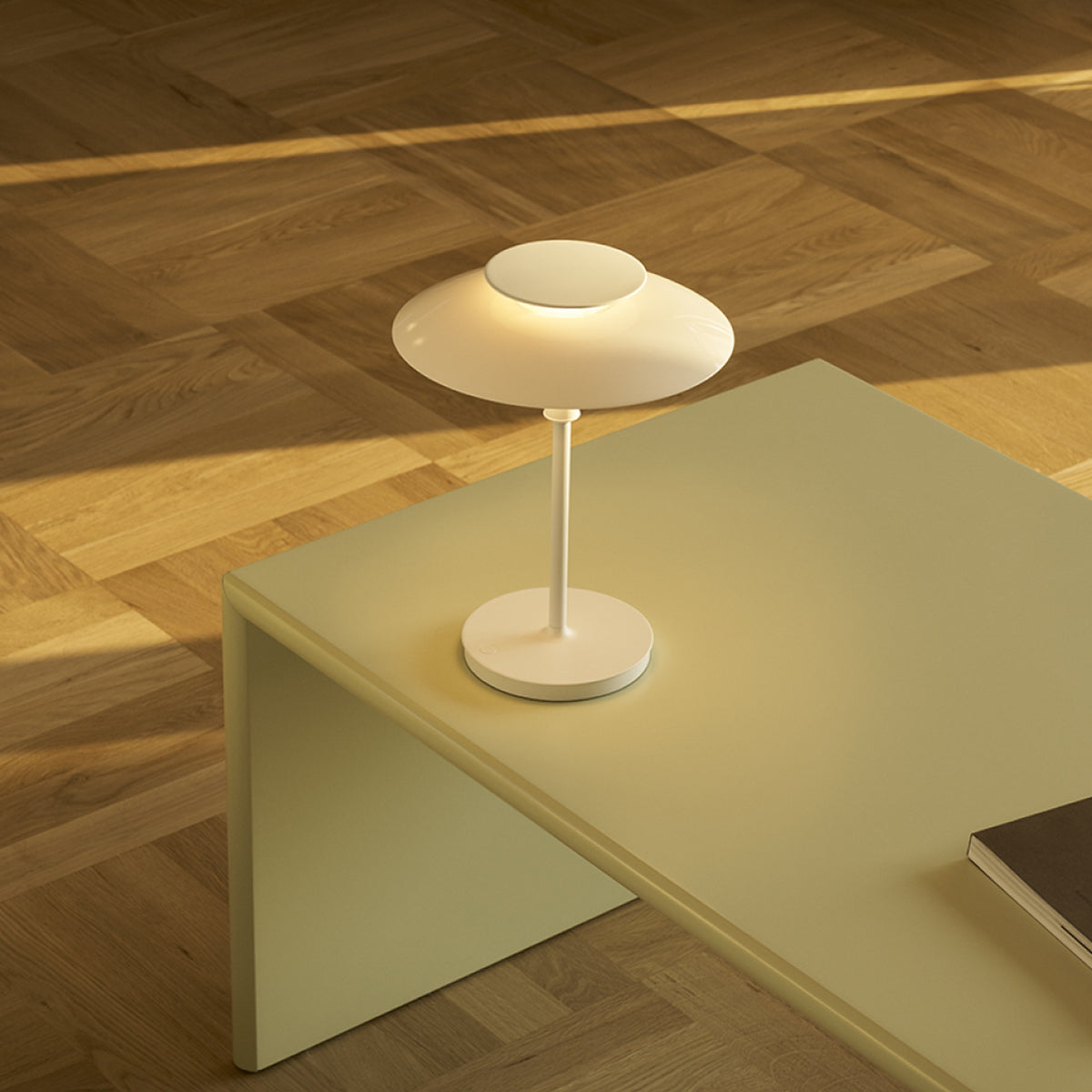 White PH 80 Portable Lamp illuminated on a pale yellow coffee table.