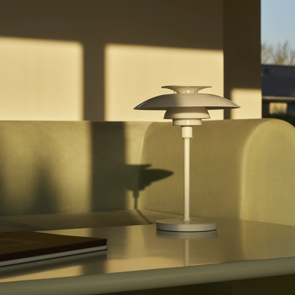 White PH 80 Portable Lamp switched off on a coffee table beside a sofa.