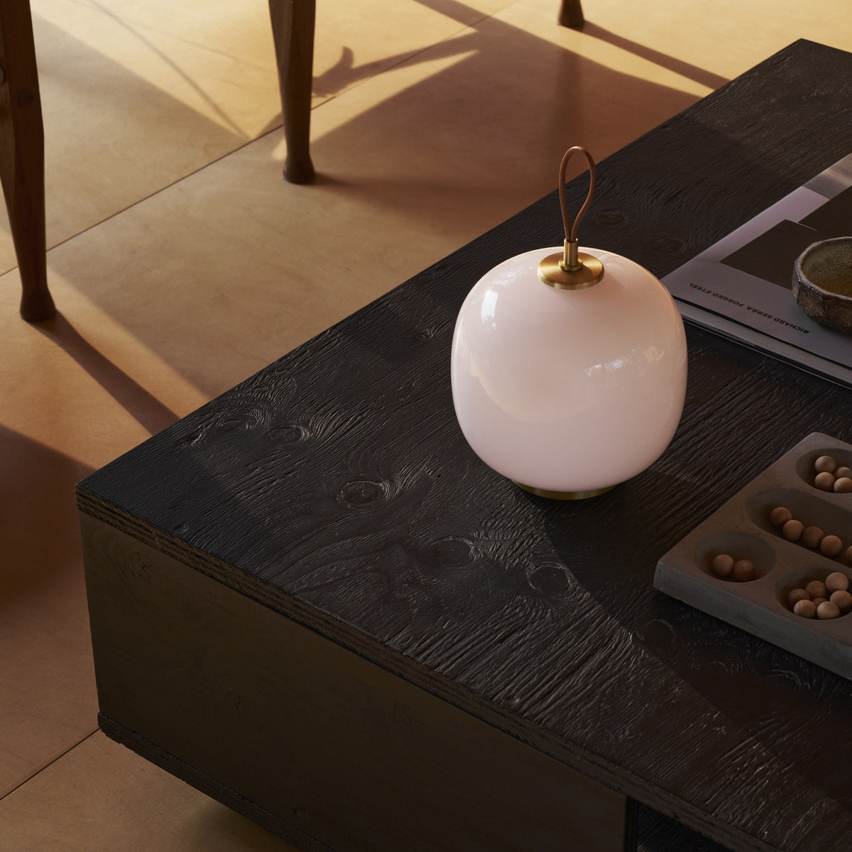 Pale Rose VL45 Portable Lamp switched off on a dark wood coffee table.