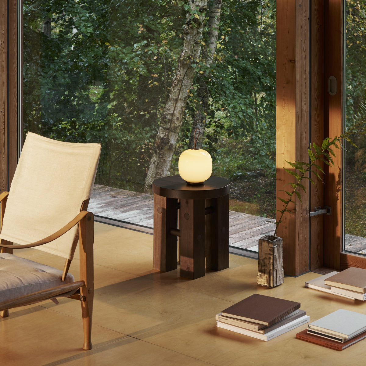 Pale Yellow VL45 Portable Lamp illuminated on a round side table beside a window.