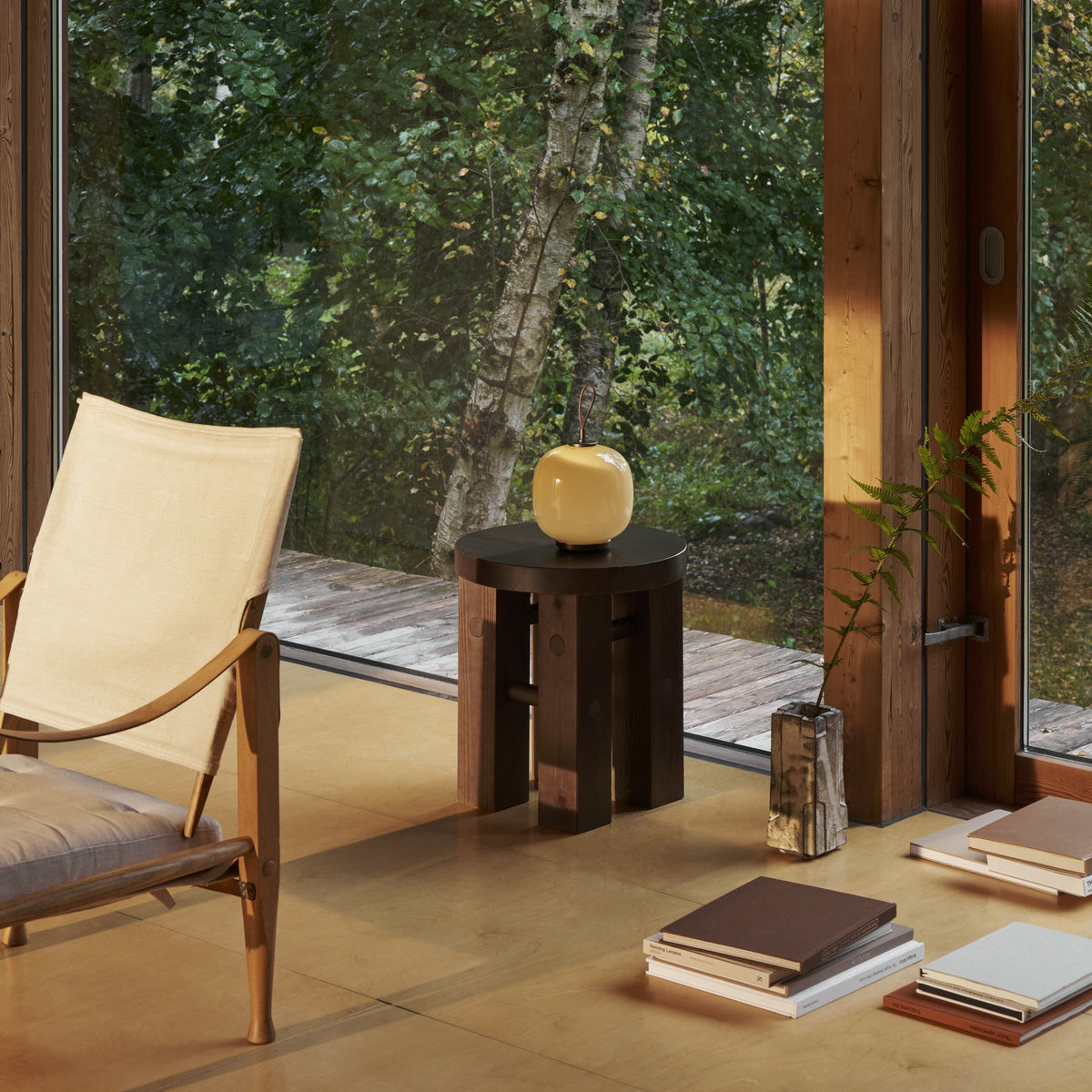 Pale Yellow VL45 Portable Lamp on a round side table beside a floor-to-ceiling window.