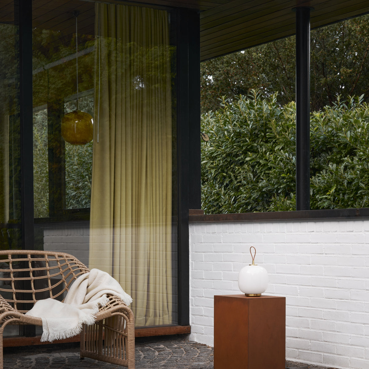 White Opal VL45 Portable Lamp switched off on a terrace pedestal, with a separate pendant in the background.