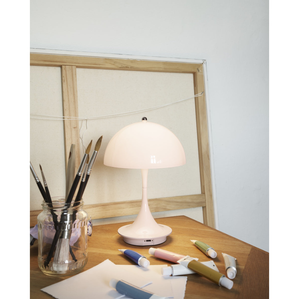 Opal pale rose Panthella 160 Portable lamp on an artist’s work table.