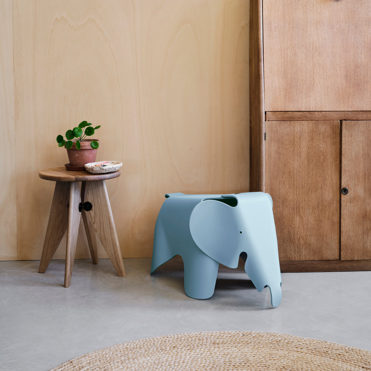Sky blue Eames Elephant beside a wooden cabinet and side table