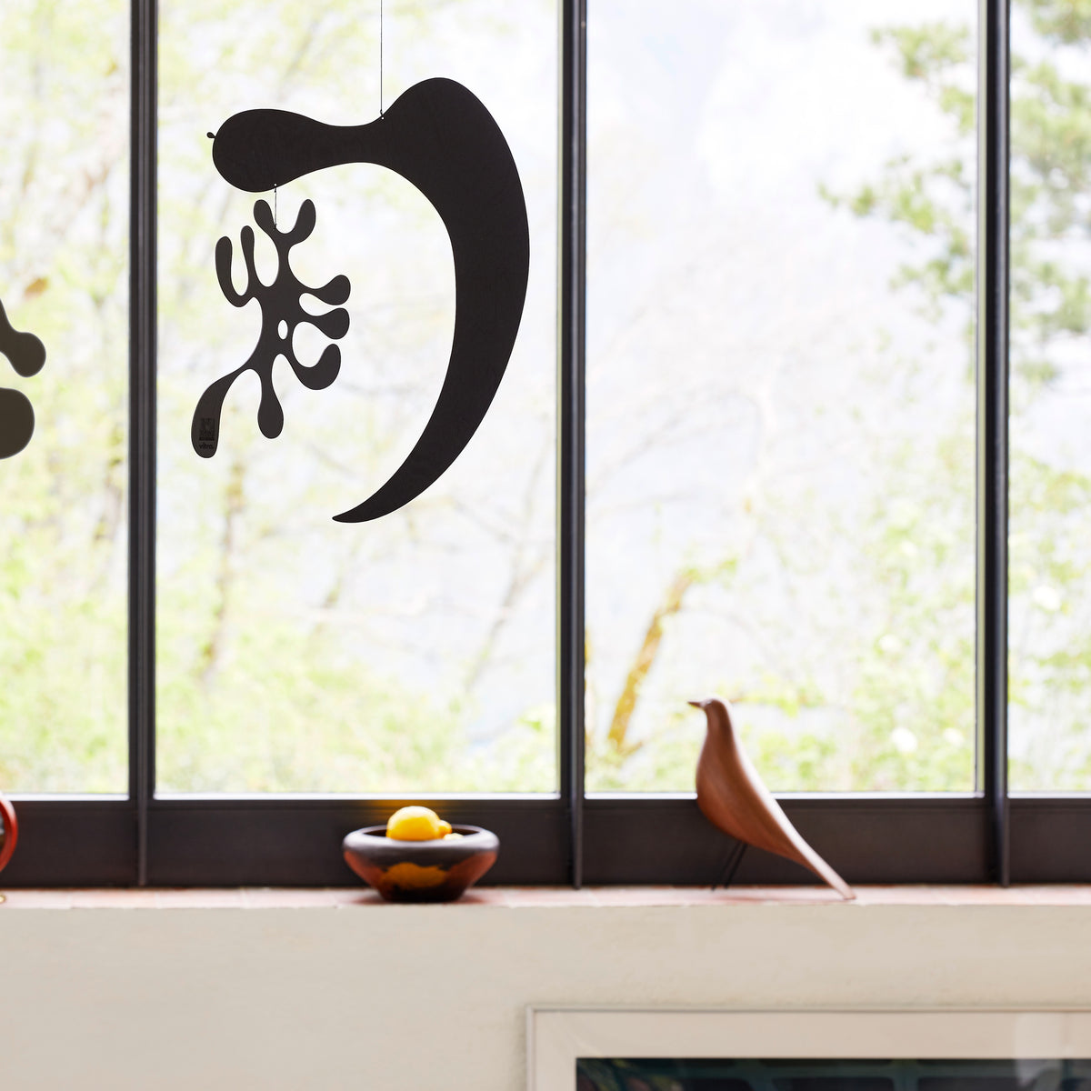 Walnut Eames House Bird displayed by a window with Plywood Mobiles; accessories sold separately