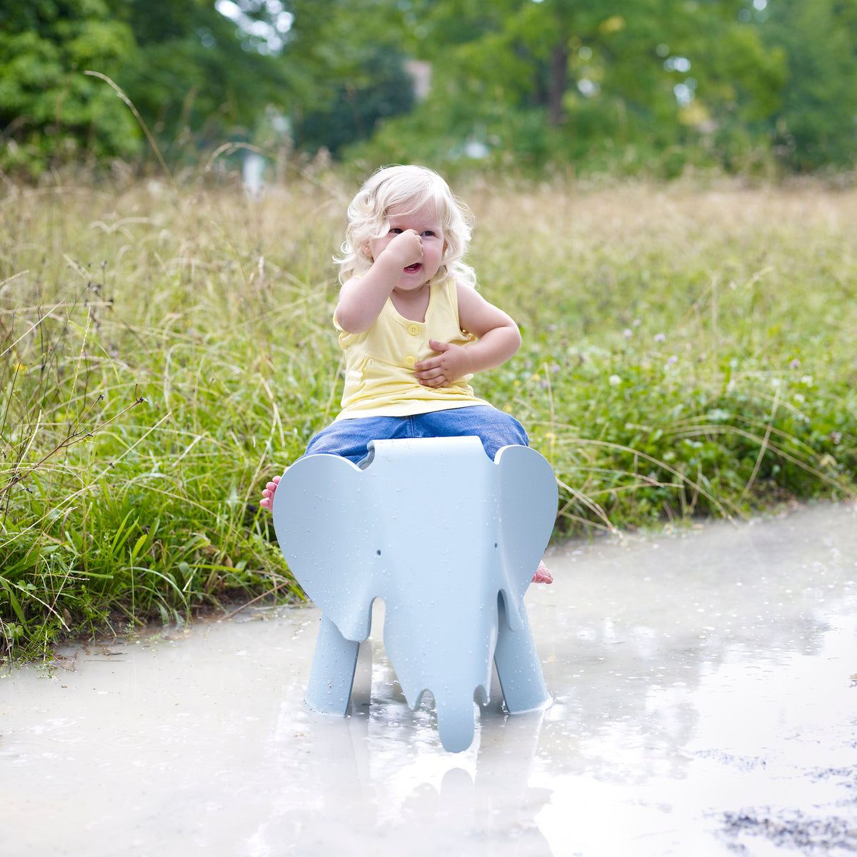Sky blue Eames Elephant shown with a child outdoors