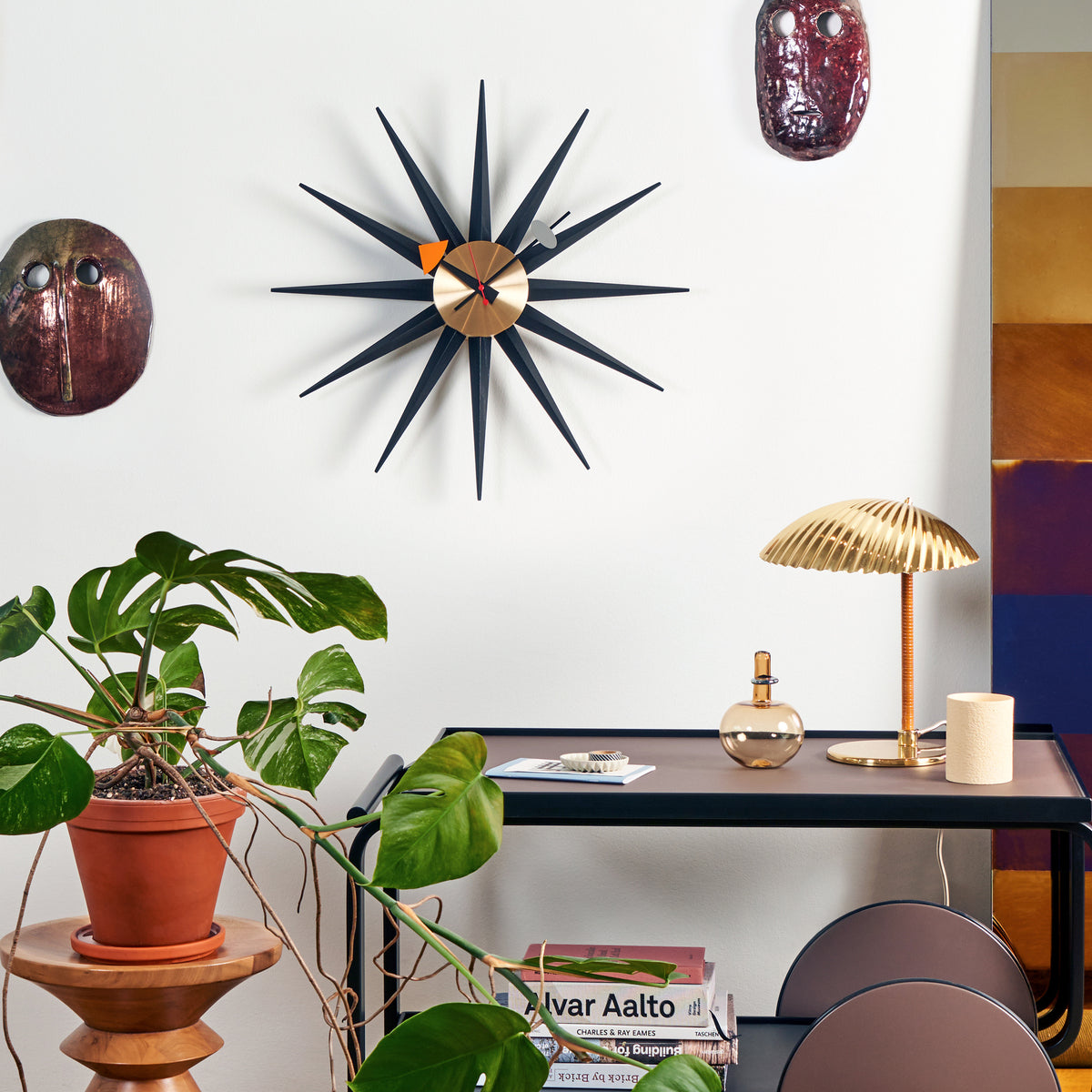 Black and brass George Nelson Sunburst Clock above a console